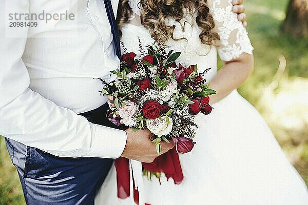 Bride and groom is holding wedding bouquet.