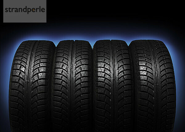 Set of four winter tires isolated on blue black background with clipping path