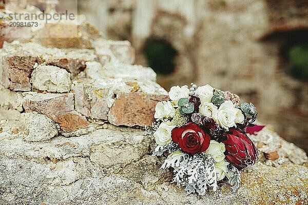 Wedding bouquet on the broken brick fence. Blurred background.