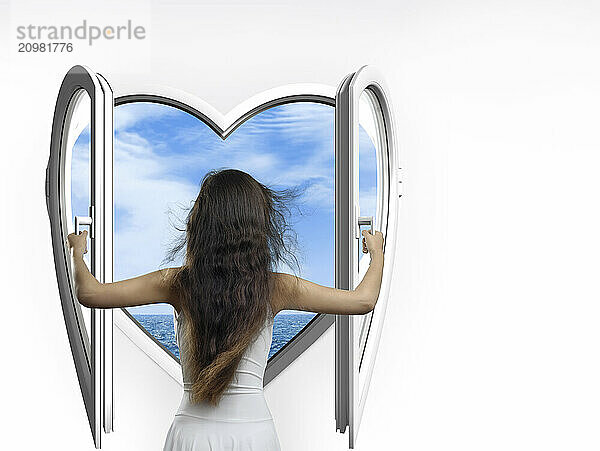 Woman opening a heart-shaped window with a view on the sea