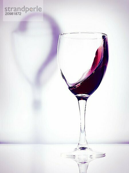 Red wine in a glass and a question mark shadow artistic conceptual photo isolated on white purple background