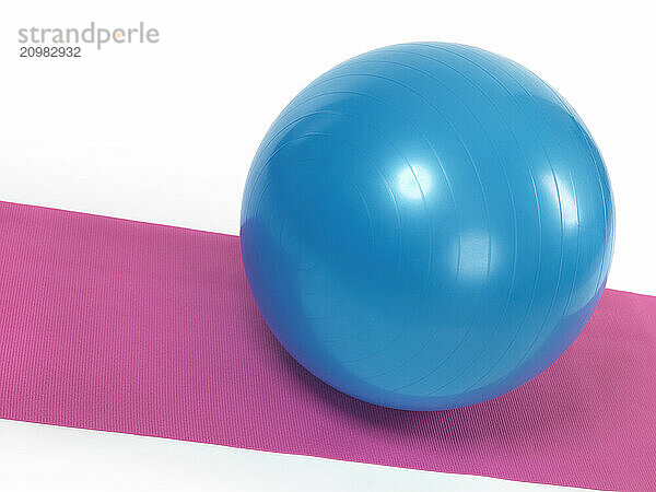 Blue fitness ball on purple mat isolated on white background