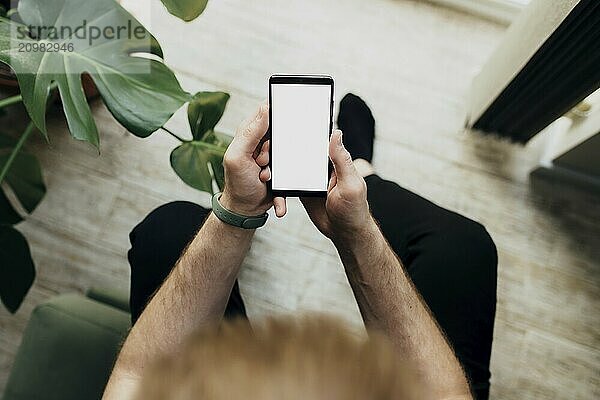 Man is holding smartphone with white screen. Blurred background.