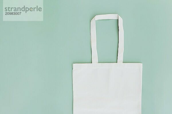 Eco white craft paper bag flat lay on green background with copy space empty advertising area. Packaging template mock up. Delivery service  reusable and recyclable resources concept