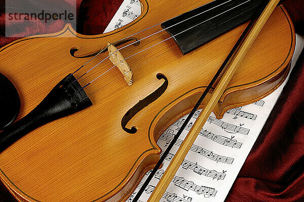 Violin and sheet music on red background musical still life