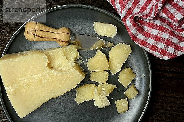 A piece of Parmesan cheese and chopped pieces of cheese on a plate