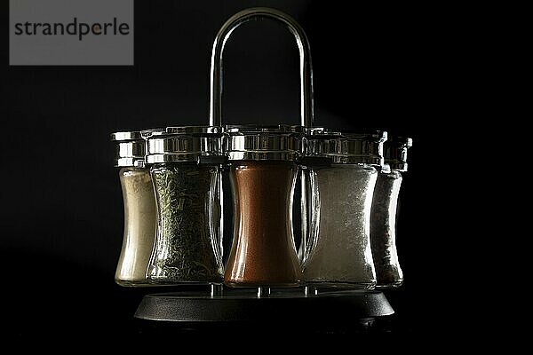 Salt and pepper shaker and and next spice containers with black background