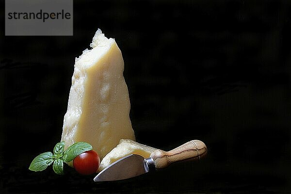 A piece of Parmesan cheese with cheese knife  basil and tomato  Italy  Europe