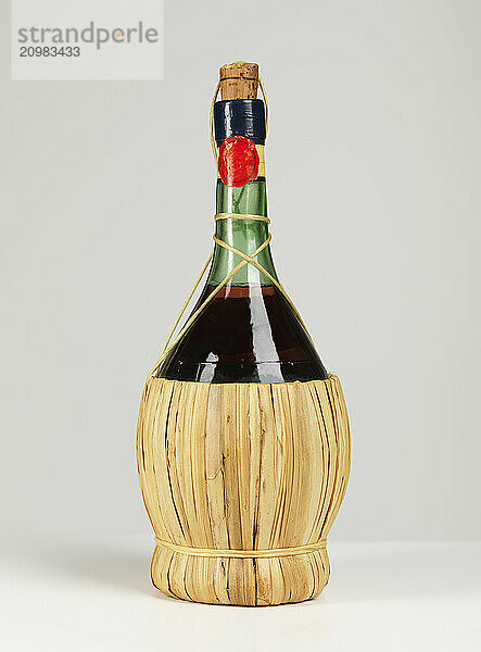 Old Italian wicker bottle of wine isolated on gray background