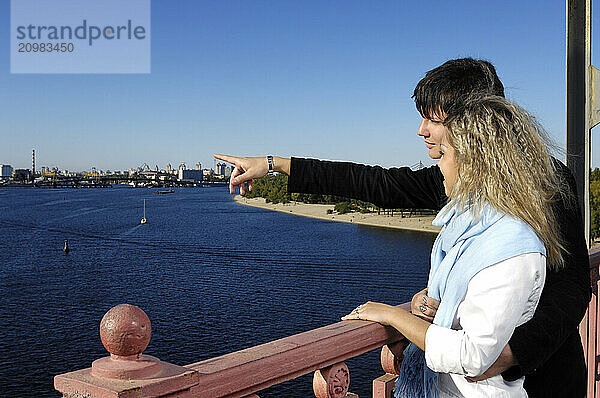 Couple  young man an a young woman on the bridge enjoying a view on the city