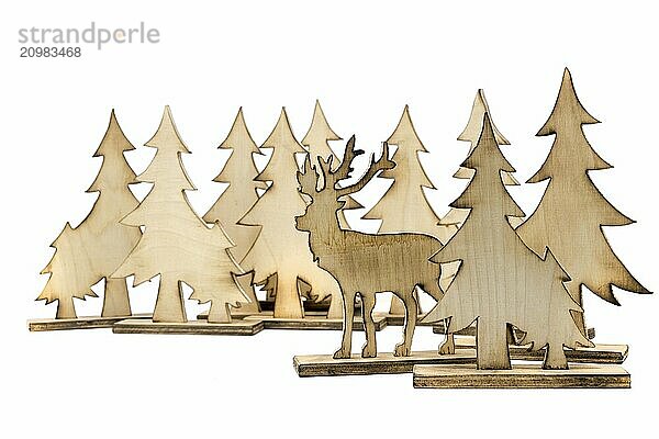 Deer figure sawn out of wood with dark edges and wooden fir trees cut out on white