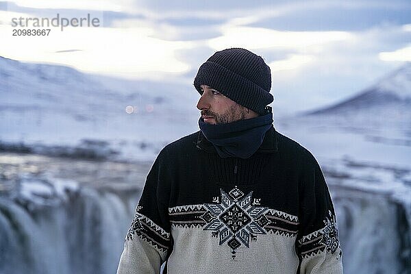 Portrait of an adventurous hiker at the frozen Godafoss waterfall in winter  Iceland  Europe