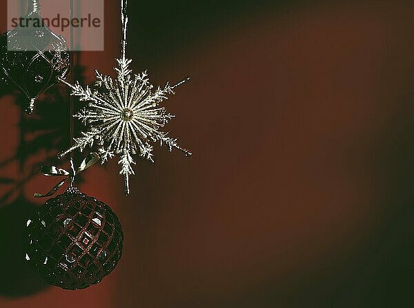 Shiny Christmas ornament on moody faded dark red background. Artistic winter holidays  new year concept with copy space