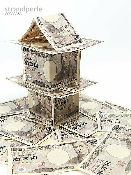 House made of Japanese Yen standing on pile of money  currency bills isolated on white background