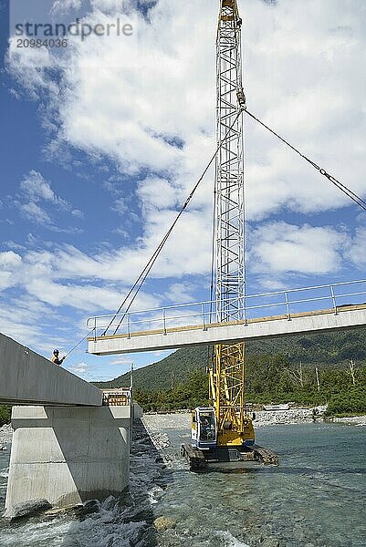 Builders construct a concrete bridge over a small river in Westland  New Zealand  Oceania