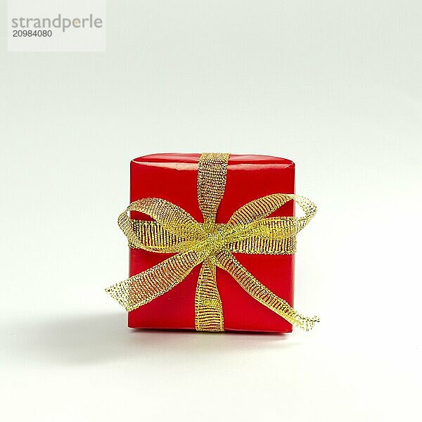 Red gift box with golden ribbon on white background.