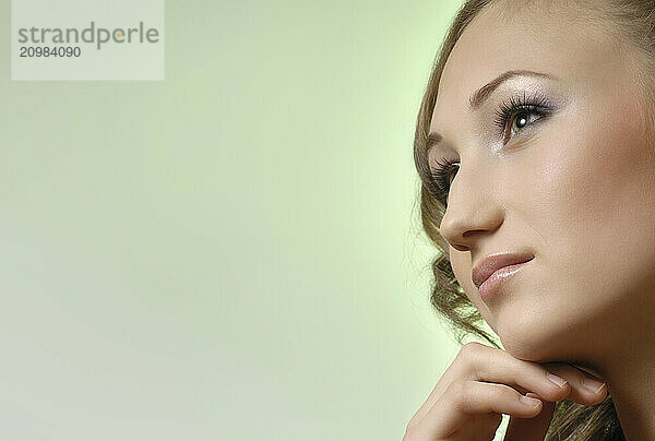 Young woman thoughtful dreamy face profile. Isolated on light green background