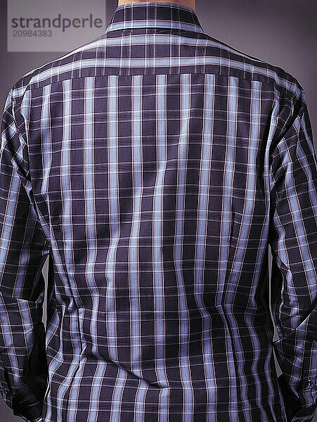 Closeup of a back of a man in stylish blue tartan shirt on grey background. Rear view