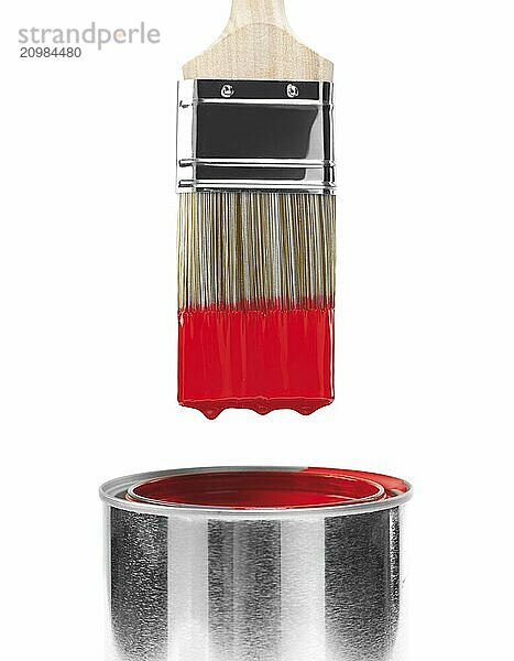 Painting brush dipped in can of red paint isolated on white background