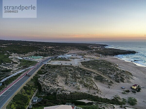 Aerial drone photo of Praia do Guincho beach sand dunes and the coastline at sunset