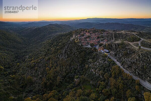 Drone aerial panorama of Sortelha historic village at sunset with lights on the castle eolic wind turbines and nature landscape  in Portugal