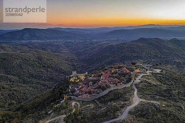 Drone aerial panorama of Sortelha historic village at sunset with lights on the castle eolic wind turbines and nature landscape  in Portugal