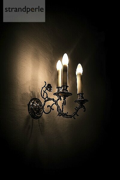 Old electric lamp on a whitewashed wall with a dark background