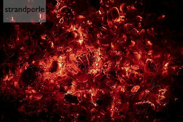 Red glowing charcoal in a campfire against a black background