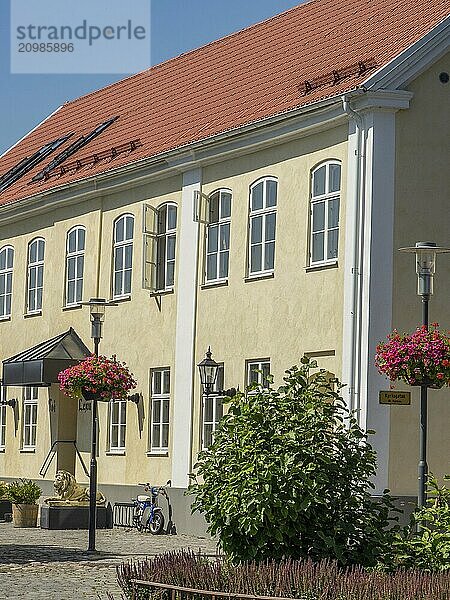 Yellow building with windows  flowers and a bicycle in front of a blue sky  some windows are open  trelleborg  sweden  baltic sea  scandinavia