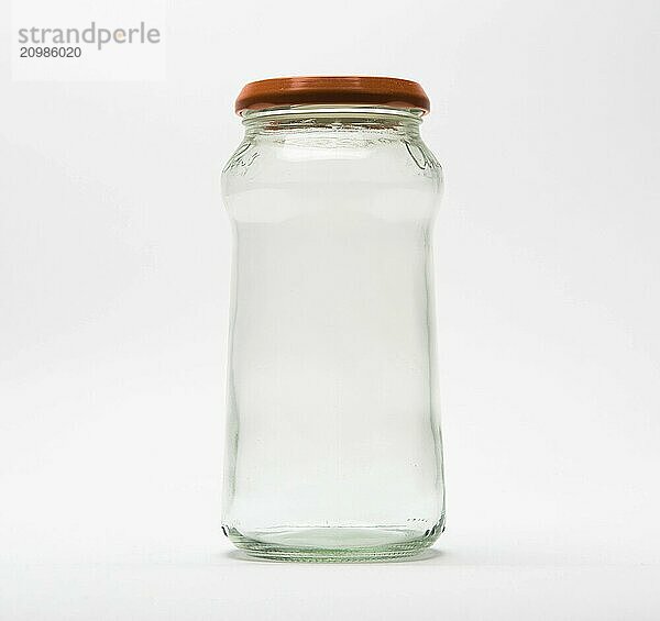 Empty glass jar with an orange lid on white background