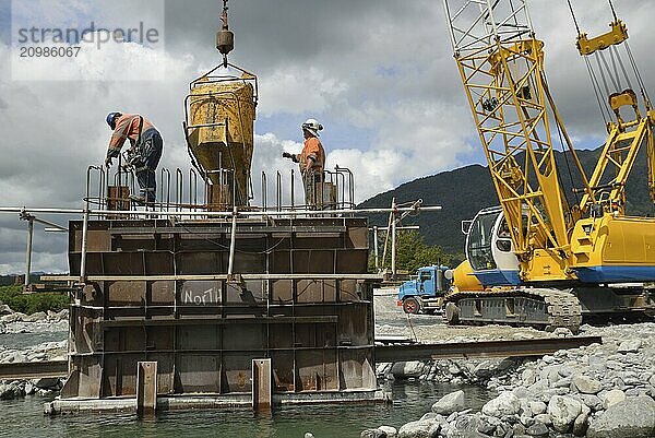 Builders construct a concrete bridge over a small river in Westland  New Zealand  Oceania