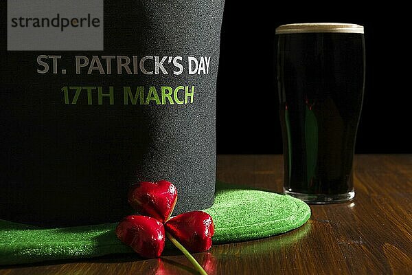 Closeup of St Patrick day with a pint of black beer  hat and shamrock over a table and black background