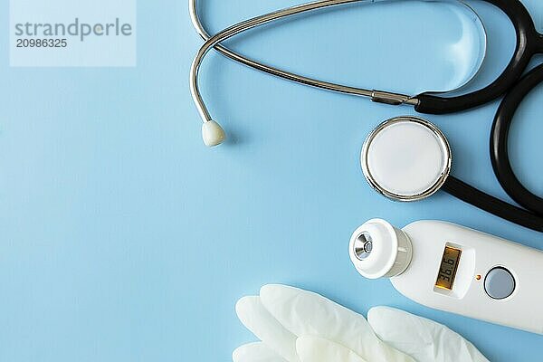 Medicine treatment concept. Electronic thermometer  phonendoscope or stethoscope  white gloves on blue background.