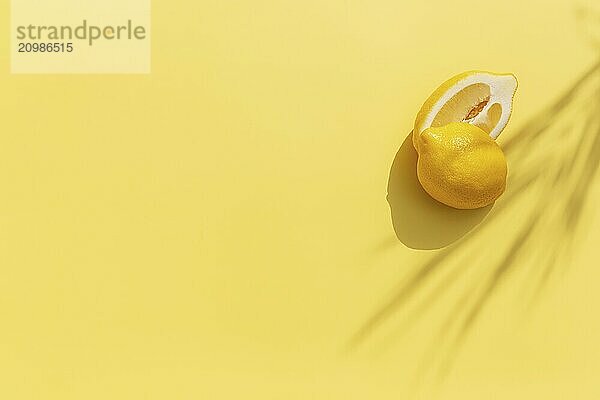 Two halved cuts of lemon with shadow from palm leaf on yellow background. Healthy eating  travel or vacation concept