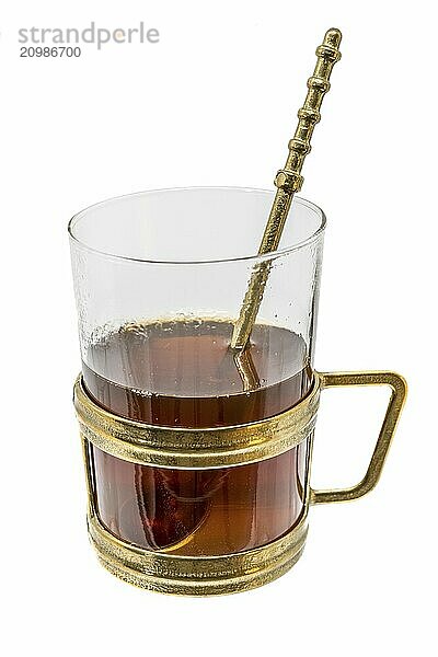 Glass with metal handle and bronze spoon filled with hot tea  painted on white