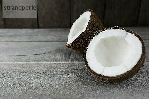 Broken coconuts on gray wooden background. White coconut pulp.