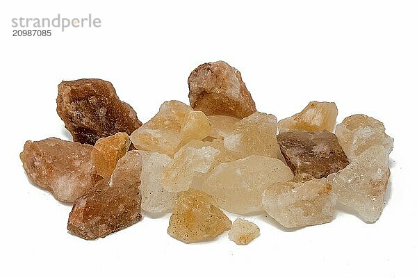 Salt stones of different colours piled up in front of a white background