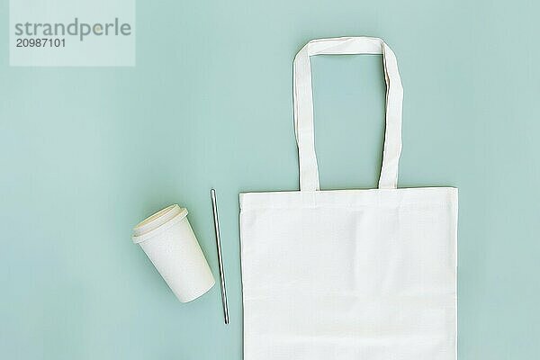 Eco white craft paper bag  metal drink straw  coffee cup on green background flat lay with copy space empty advertising area. Mock up for delivery service  reusable and recyclable resources concept