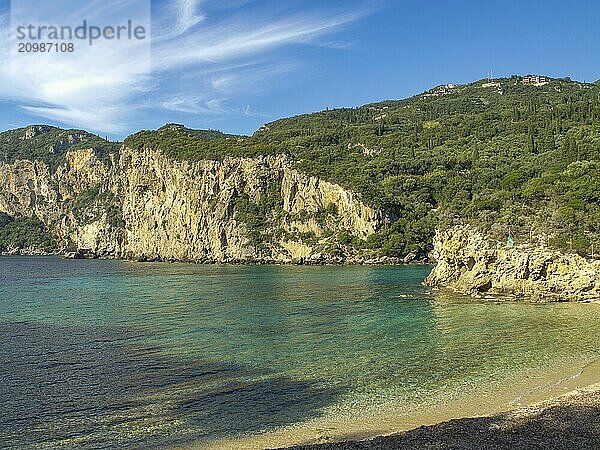 Wide view of a secluded beach and sparkling turquoise sea with rocky cliffs and green background  corfu  mediterranean sea  greece