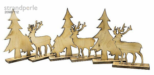 Stag figure sawn out of wood with dark edges and wooden fir trees cut out on white