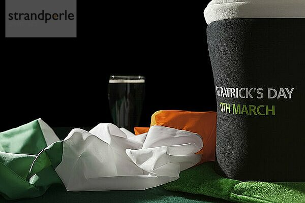 St Patrick day with a pint of black beer  hat and irish flag over a green table and black background