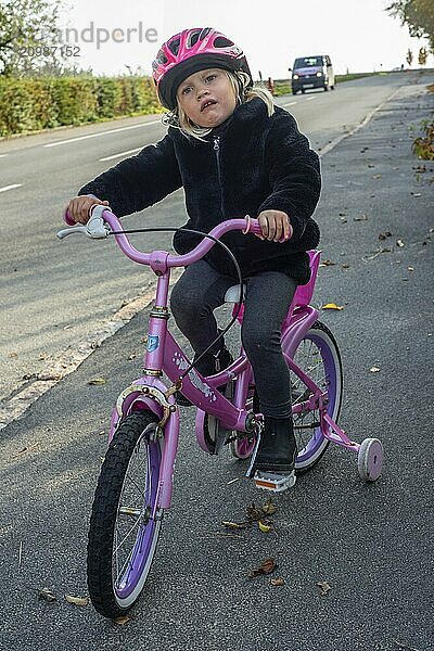 Scared and insecure blonde girl  3 years old  alone on a bicycle in traffic in Ystad  Skåne County  Sweden  Scandinavia  Europe