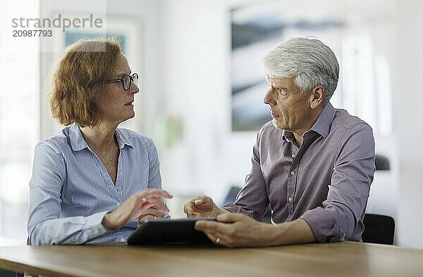 Symbolic photo. A woman and a man sit together at a table with a tablet and talk. Berlin  13.08.2024