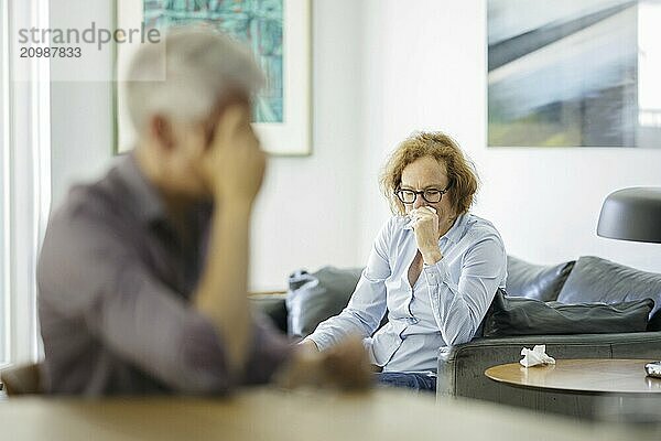 Symbolic photo on the subject of problems in a partnership. An older woman and an older man sitting at home. Berlin  13.08.2024