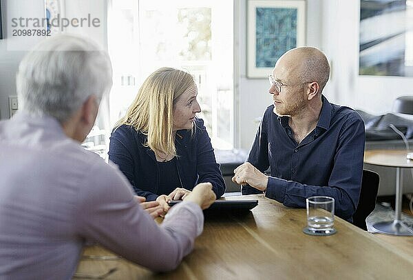 Symbolic photo on the subject of counselling. A young woman and a young man sit together at a table at home and receive counselling. Berlin  13.08.2024