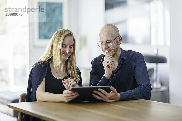 Symbolic photo. A woman and a man sit together at a table with a tablet and talk. Berlin  13.08.2024