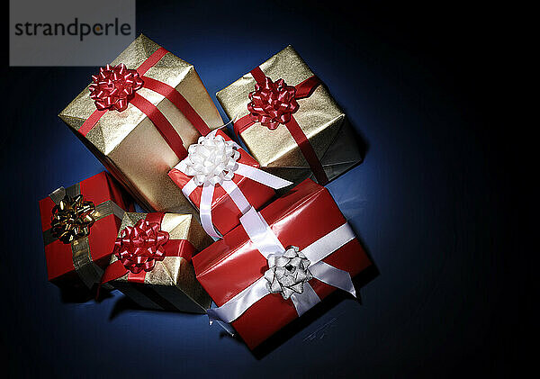 Pile of Christmas gift boxes illuminated in darkness isolated on dark blue background