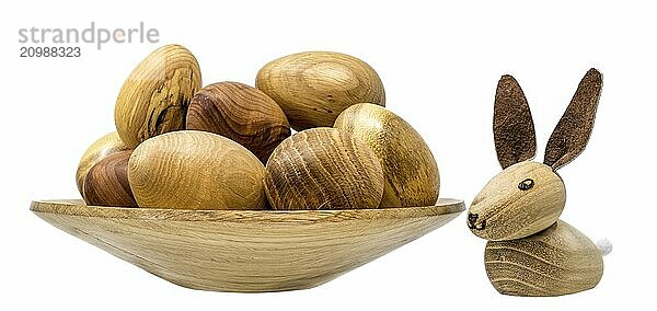 Hand-turned wooden eggs in a small wooden bowl with toy Easter bunnies painted on white