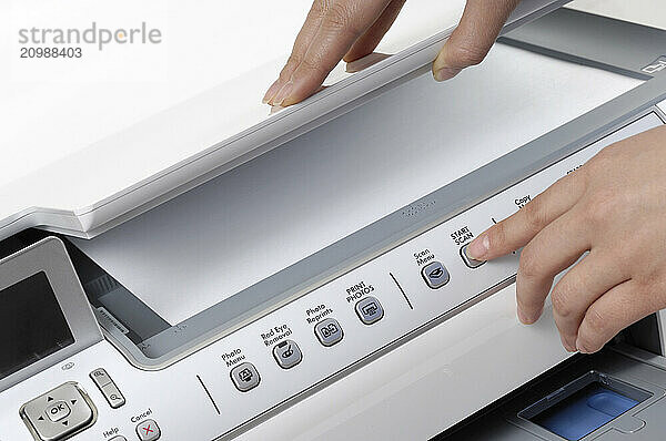 Stock photo of a Person scanning a paper in All-In-One printer scanner copier Close-up of hands