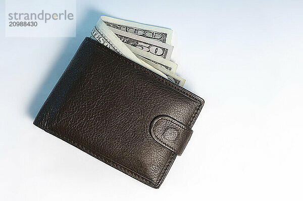 Brown leather wallet with US dollar bills sticking out of it Isolated on white